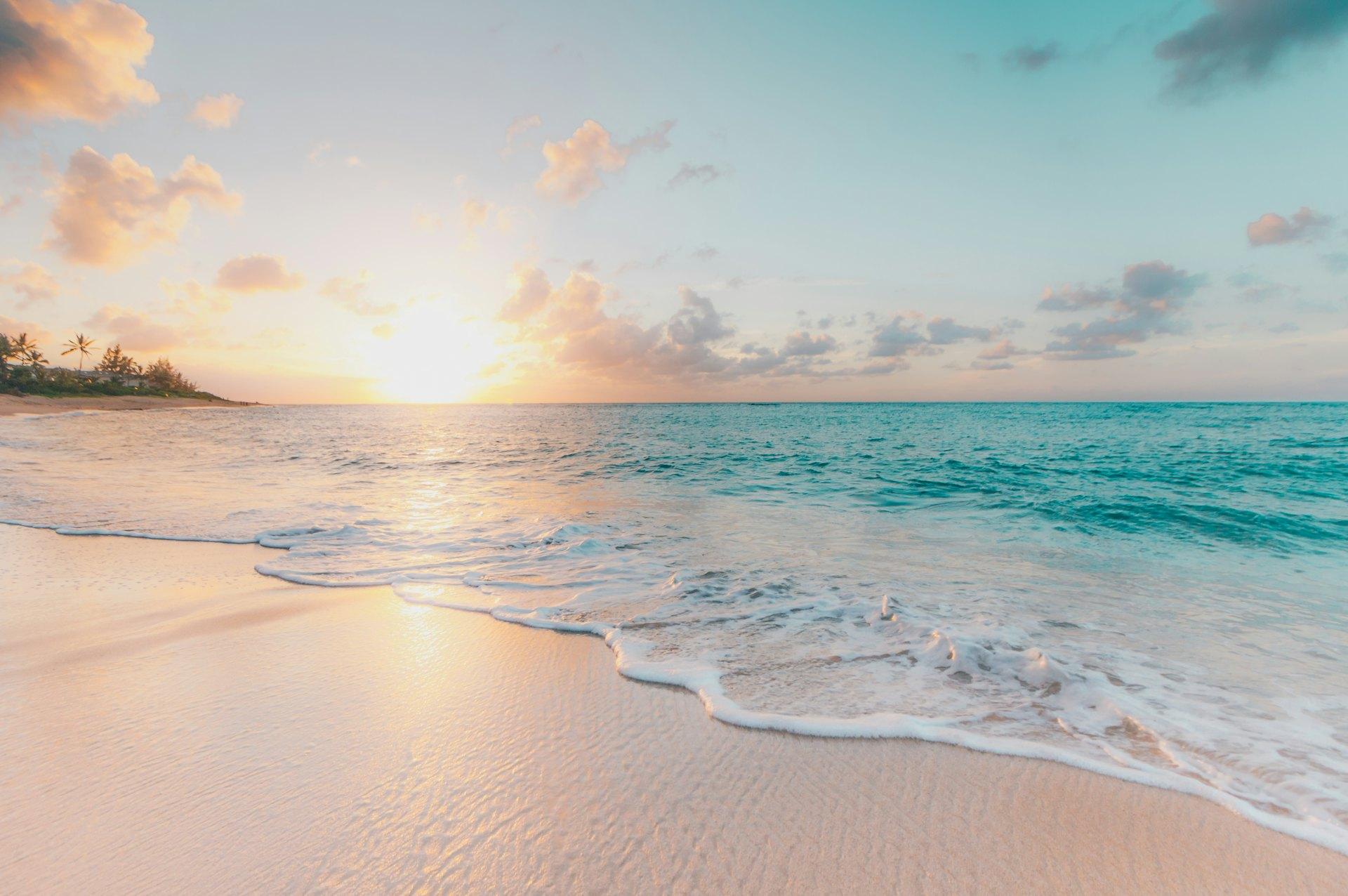 Quiet beach at sunset with pale sand and turquoise water
