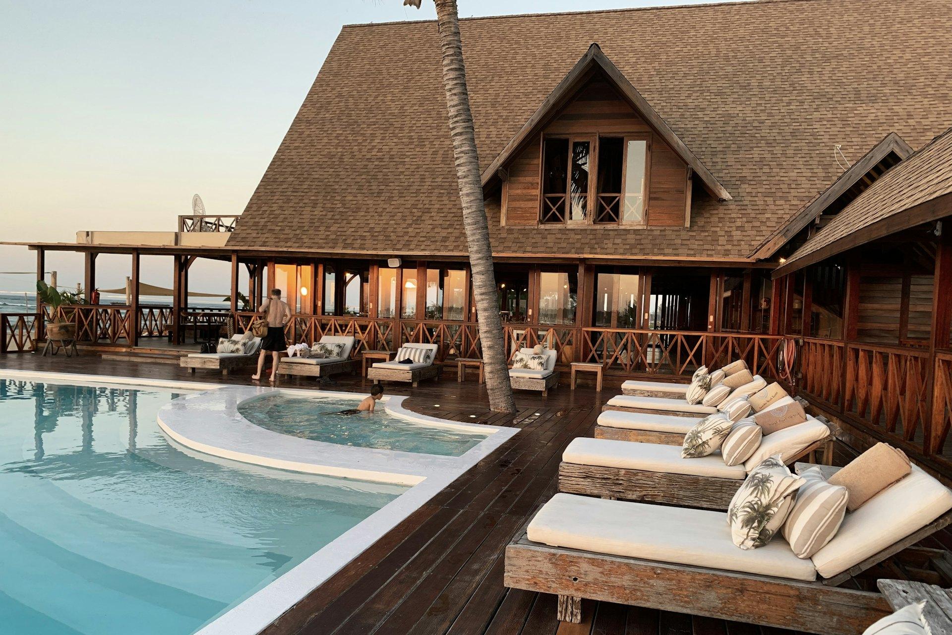 Hotel terrace with loungers beside a pool at sunset